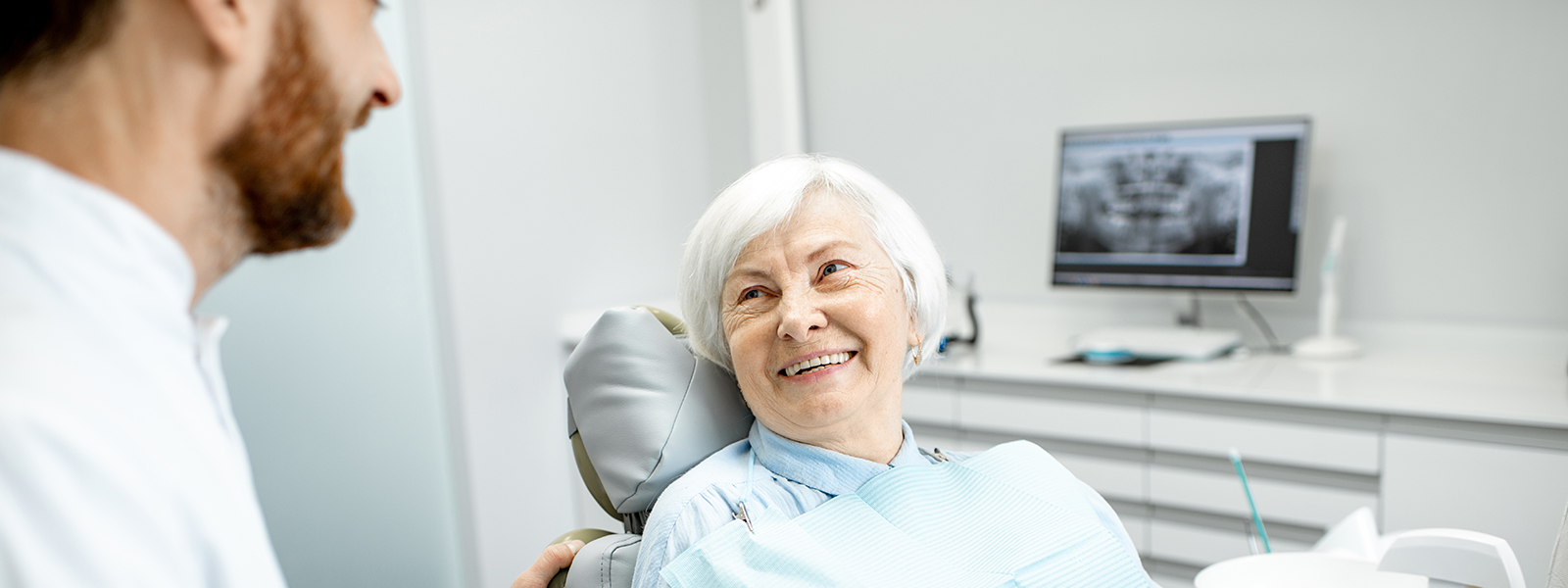 A photo of an elderly lady smiling at the dentist with excellent quality dental bridges and crowns.